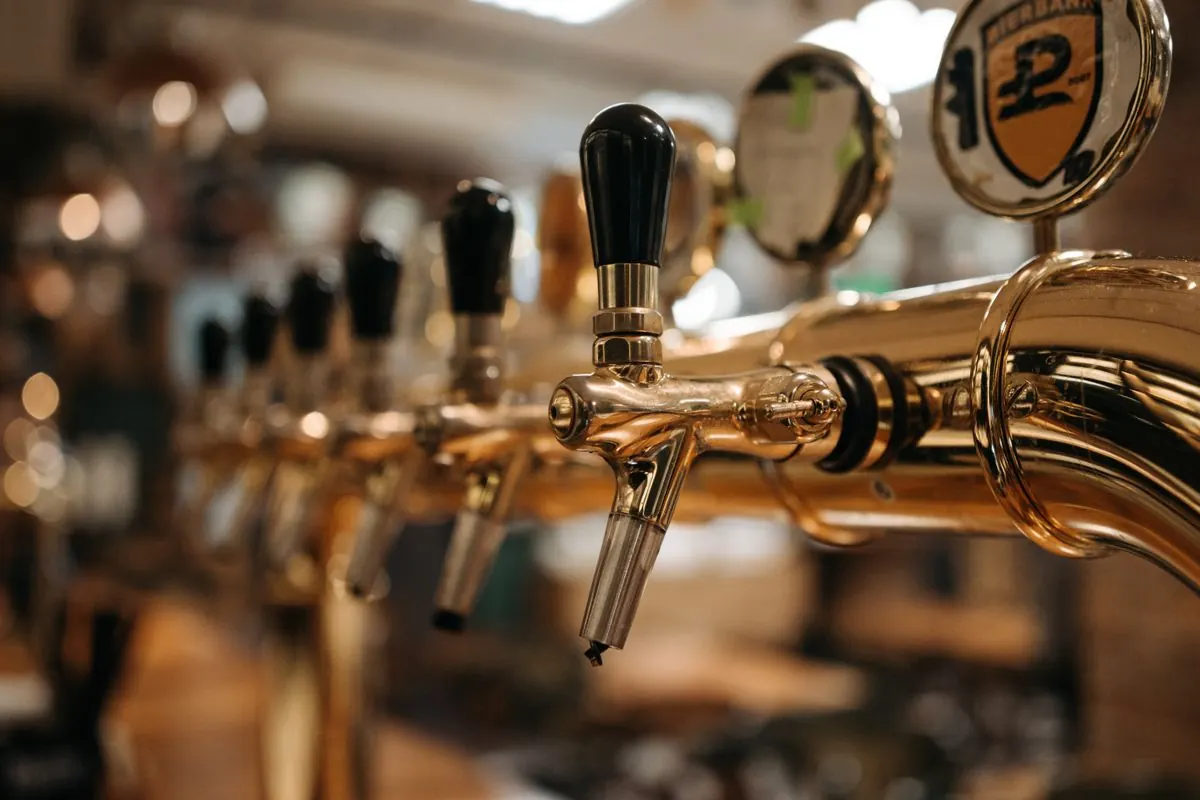 Row of brass beer taps at a brewery taproom