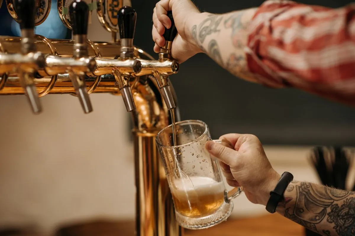 Bartender pouring a pint from the taps, where a brewery taproom POS runs open tabs