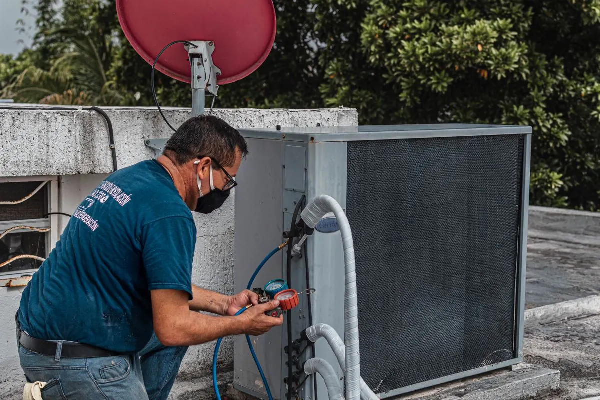 HVAC, plumbing & electrical payment processing on site: technician servicing an outdoor AC unit
