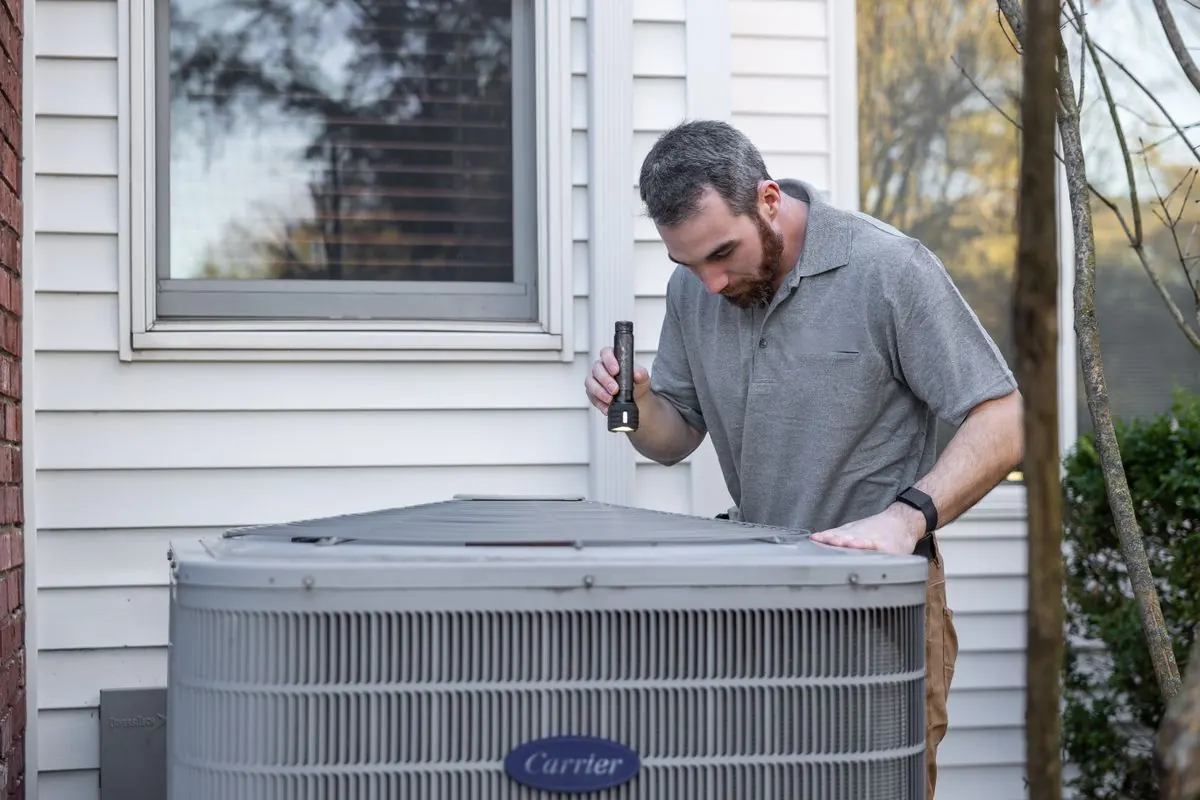 Technician inspecting an outdoor HVAC unit