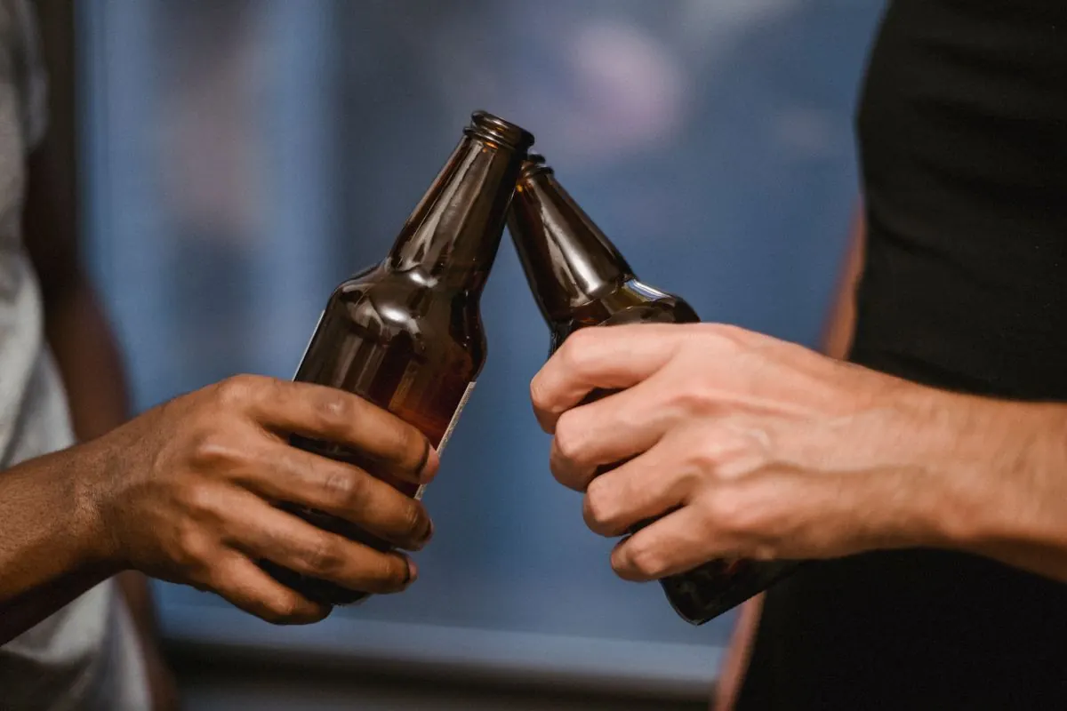 Two taproom guests toasting with bottles of beer